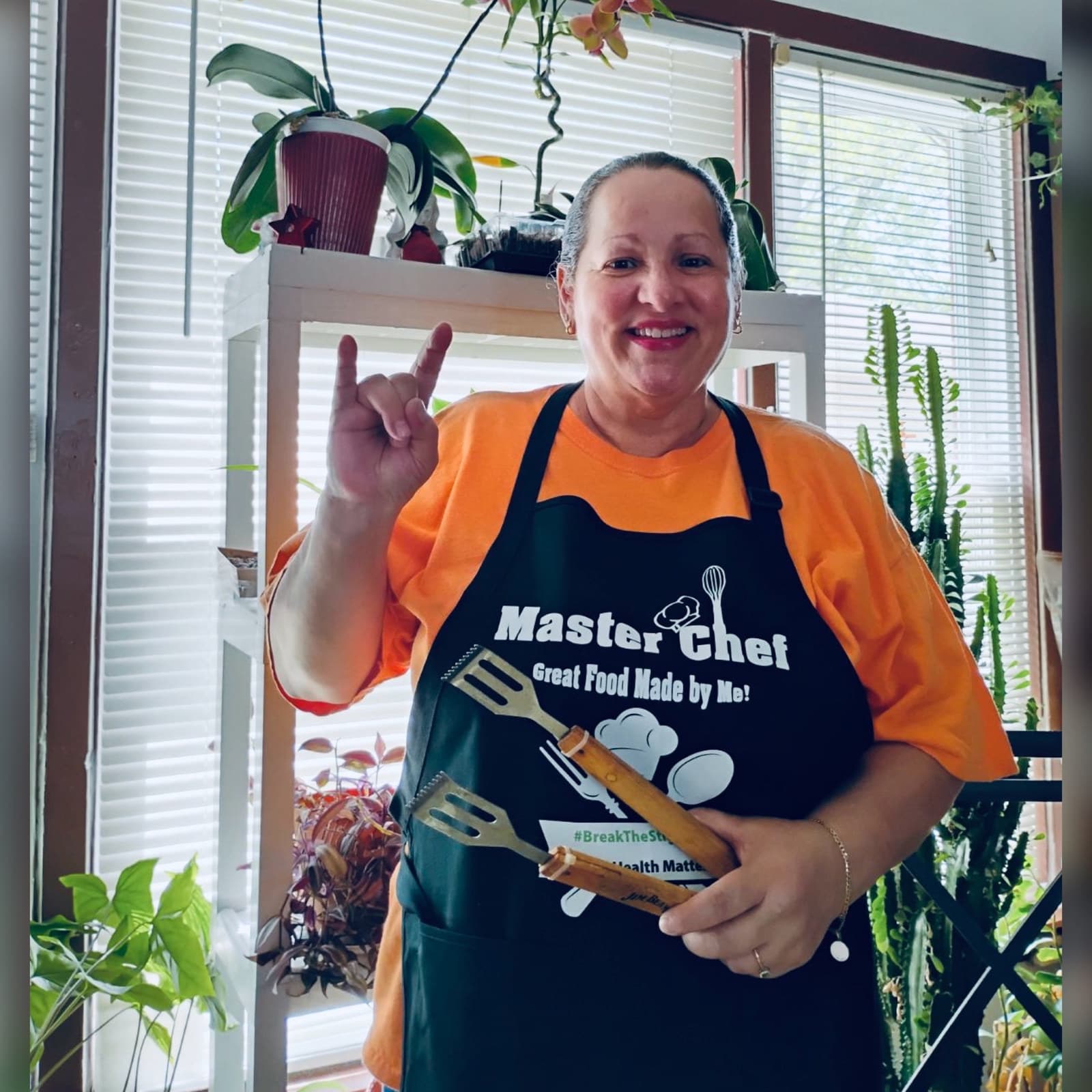A supporter in an apron holding kitchen utensils
